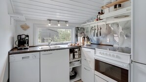 A modern kitchen with white cabinetry, a built-in oven, and a coffee machine. - "Landolf" - 250m from the sea by Interhome (Hals)