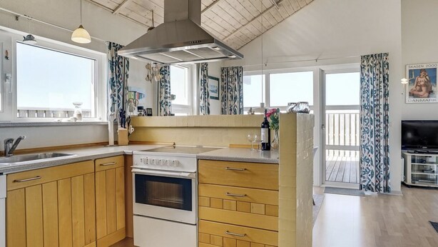 A modern kitchen with wooden cabinets, a built-in oven, and a large window.