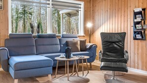 En moderne stue med en blå sofa, en sort lænestol og et lille bord med kaffepotte.