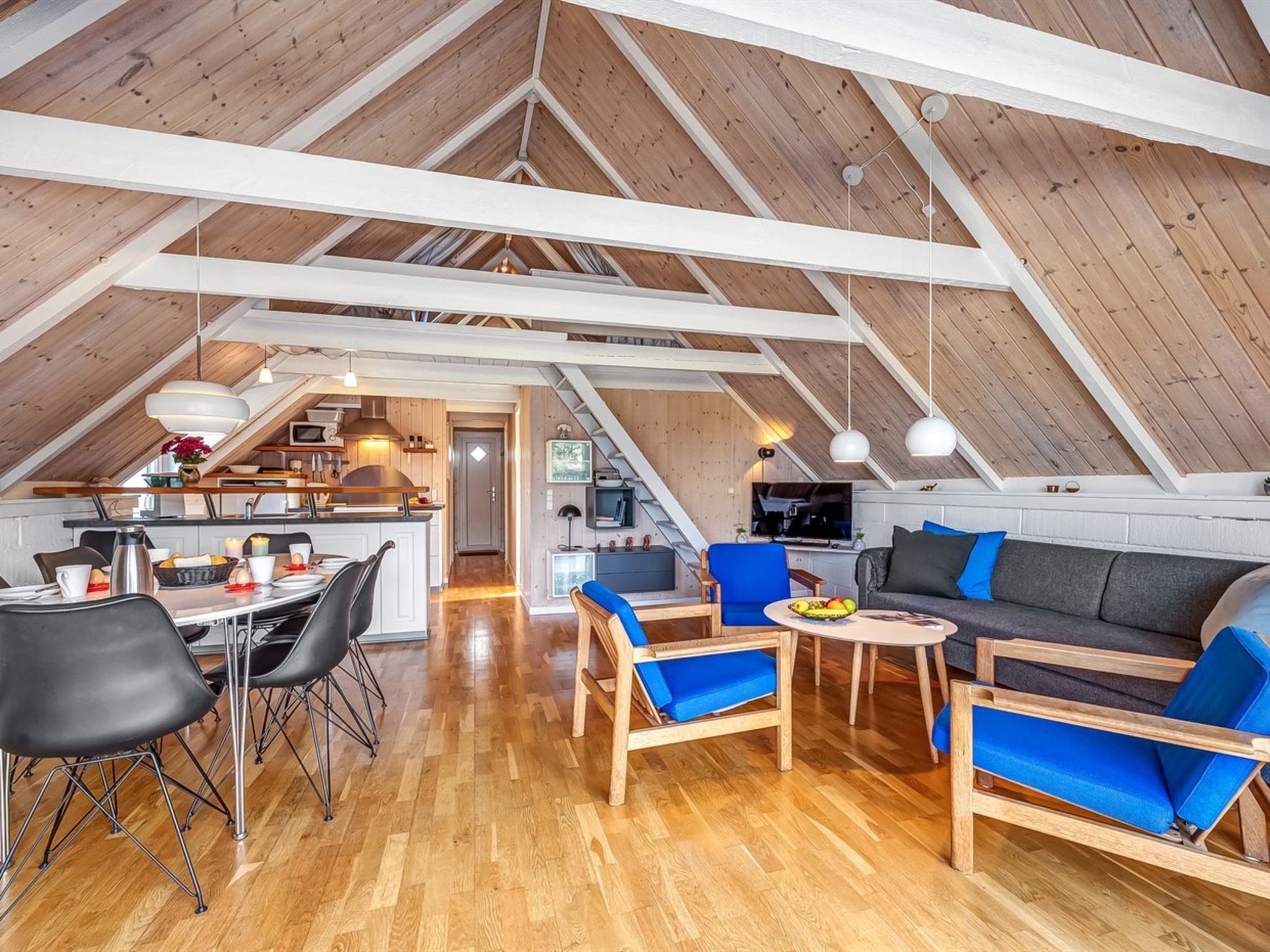 Un loft spacieux avec de hauts plafonds, des poutres apparentes, un coin cuisine et un espace salon.