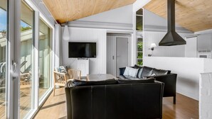A modern living room with a black leather sofa, a flat-screen TV mounted on the wall, and a wooden ceiling. - "Sulevi" - 200m to the fjord by Interhome (Vestervig)