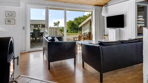 A modern living room with a fireplace, black leather sofas, a TV, and a large sliding glass door leading to an outdoor patio. - "Sulevi" - 200m to the fjord by Interhome (Vestervig)