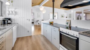 A modern kitchen with white cabinetry, a wooden ceiling, and a black range hood. - "Sulevi" - 200m to the fjord by Interhome (Vestervig)