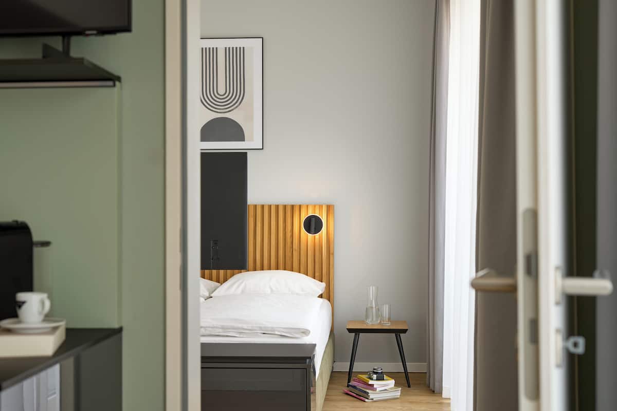 Quarto de hotel com cama, mesa de cabeceira e uma obra de arte pendurada na parede.