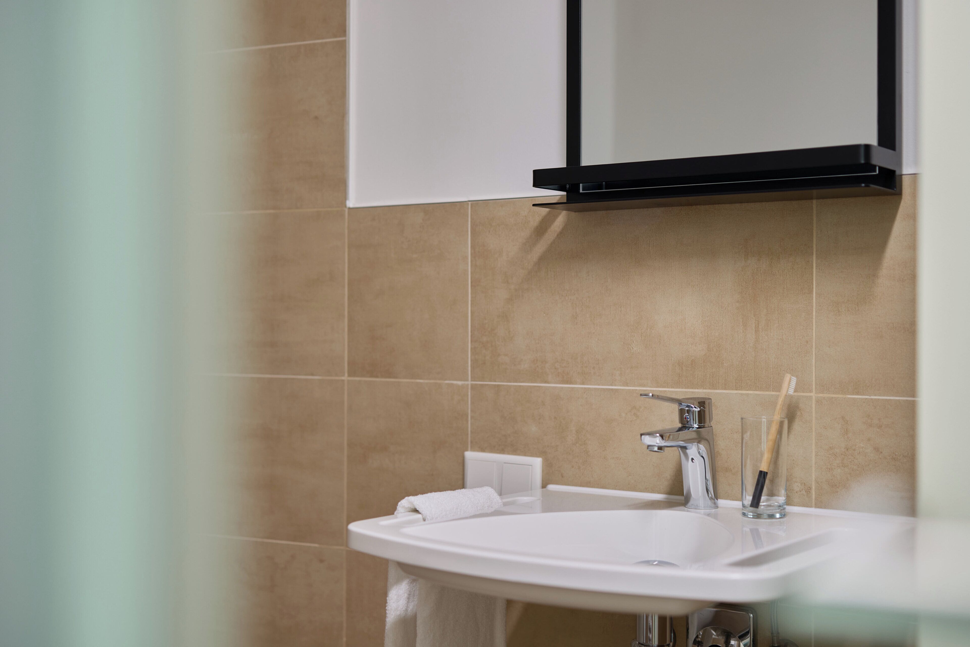 A bathroom with a white sink, a mirror, and a towel rack.
