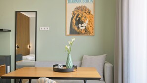 A modern room with a dining table, a sofa, a mirror, a poster, and a vase with flowers. - appartello - smarttime living Berlin (Berlin)