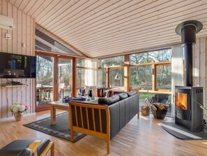 Ein modernes Wohnzimmer mit Kamin, Holzböden und großen Fenstern.