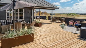 A wooden deck with outdoor furniture, a covered seating area, and a view of the surrounding landscape.