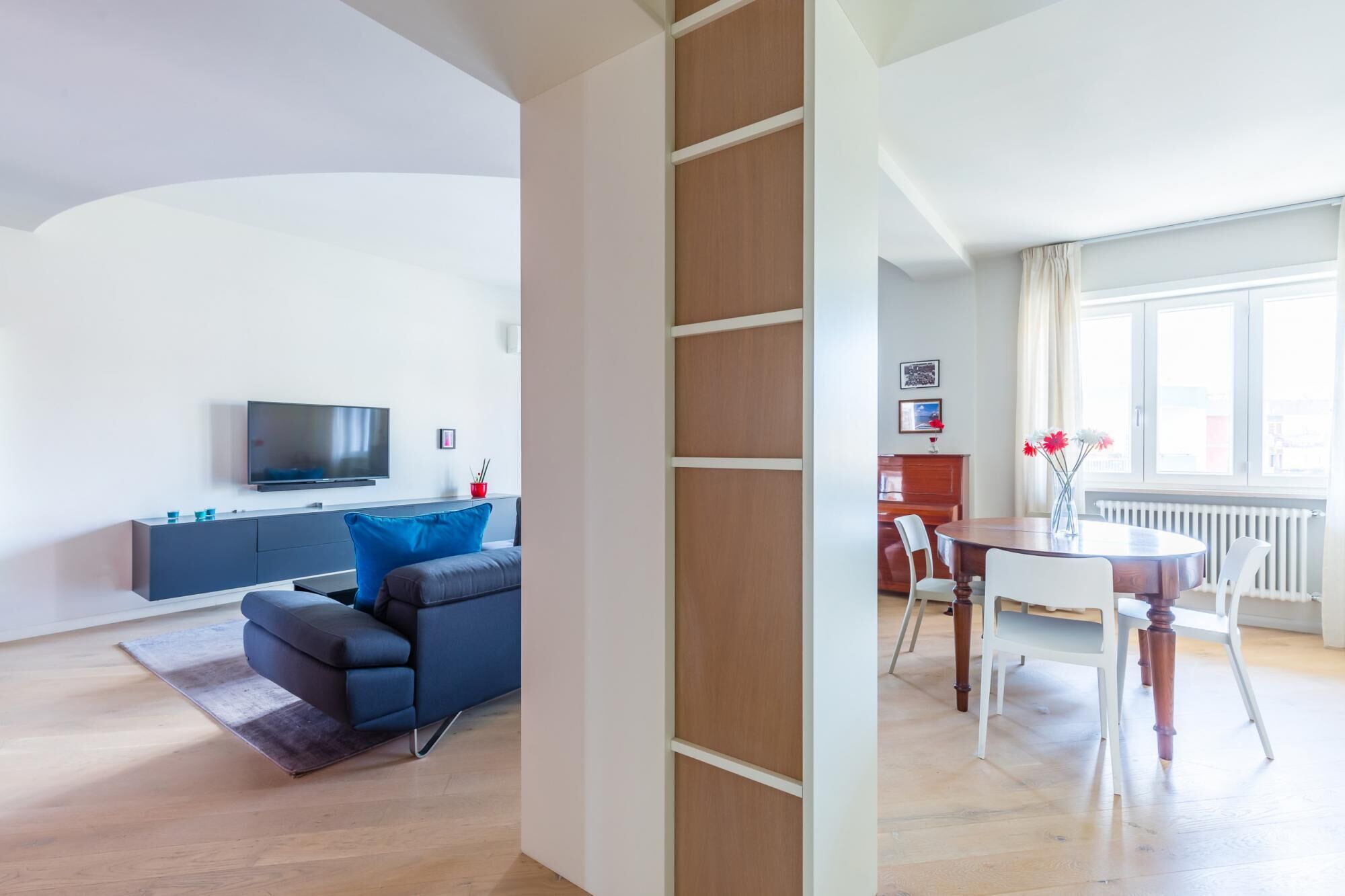 Un salon moderne comprenant un canapé, un téléviseur et un coin repas avec une table et des chaises.