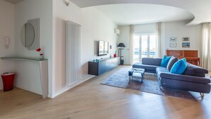 A modern living room with a sofa, a TV, a glass table, and a red trash bin. - Casa di Cami by Wonderful Italy (Naples)