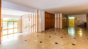 A spacious hallway with wooden flooring, a glass door leading outside, and a staircase with a yellow accent. - Casa di Cami by Wonderful Italy (Naples)