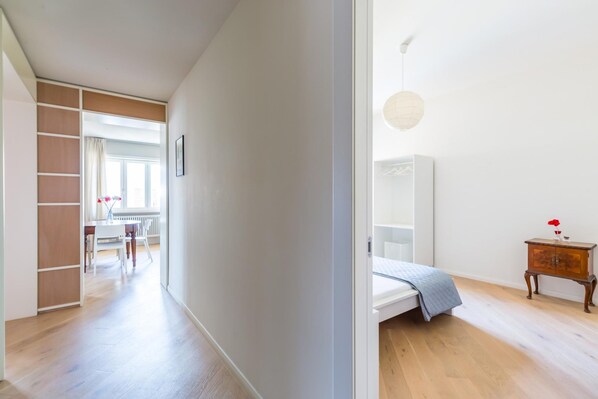 Une chambre à coucher moderne avec un lit, une table de chevet et un petit meuble en bois.