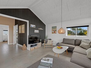 A modern living room with a sofa, a coffee table, a TV, and a dining area with a table and chairs.
