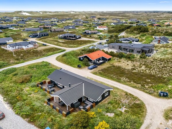 A residential area with houses, a paved road, and a grassy landscape.