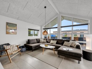 A modern living room with a sectional sofa, a round coffee table, and a large window offering a view of the outside.