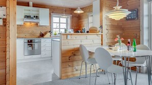Een moderne keuken met houten wanden, witte kastjes en een centraal kookeiland met zitplaatsen.