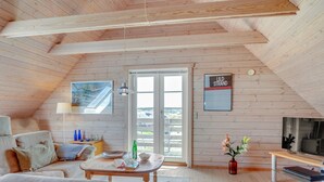 Een gezellig loft-slaapkamer met een schuine wand, een groot raam, een bed, een bureau en een televisie.