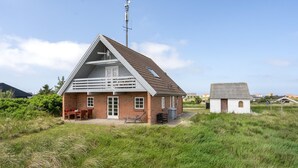 Een laag gebouw met een schuin dak, een klein aangebouwd gedeelte en een gazon ervoor.