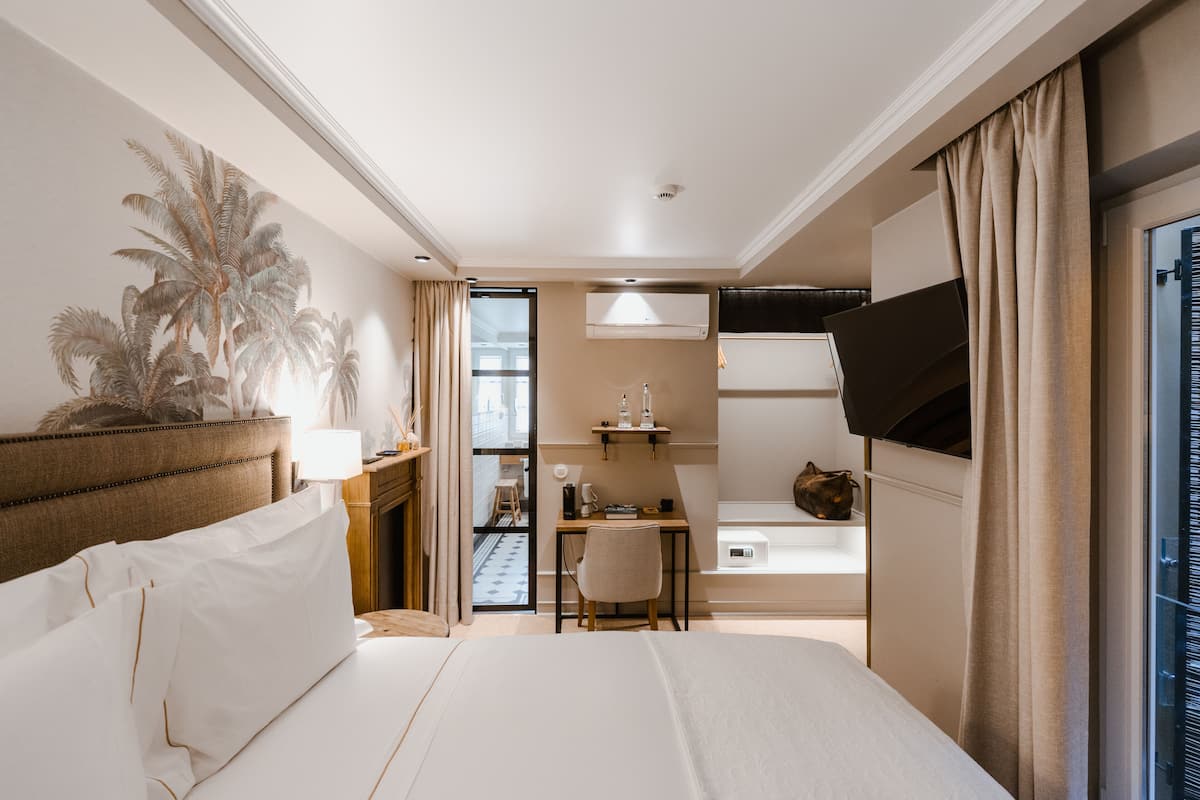 Een hotelkamer met een bed, een bureau, een stoel, een televisie en een groot raam.
