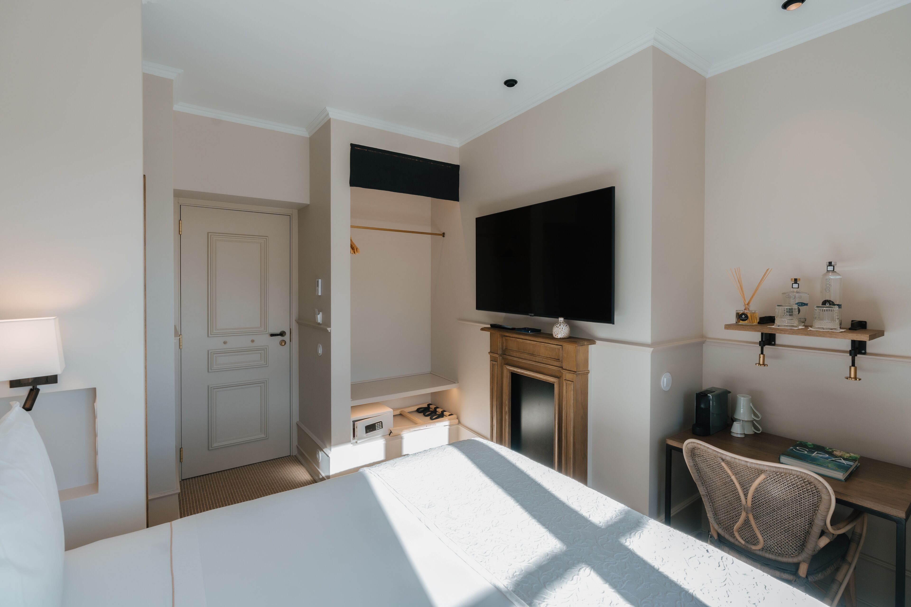 Habitación de hotel con cama, televisor sobre la chimenea, escritorio con silla y armario.