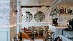 A restaurant with brick walls, round mirrors, and a bar area with bottles and glasses.
