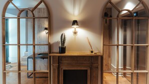 A room with a wooden fireplace, a wall-mounted lamp, and a cactus on the mantel.