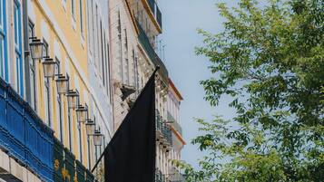 Ein Gebäude mit mehreren Balkonen, einer Flagge mit dem Schriftzug 'ALMALUSA' und einem Baum im Vordergrund.
