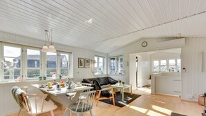 A spacious living area with a dining table, chairs, a sofa, and a kitchen area.