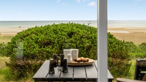 A table with binoculars and a plate of muffins, overlooking a beach with a clear view of the ocean. - "Elpida" - 100m from the sea by Interhome (Glesborg)