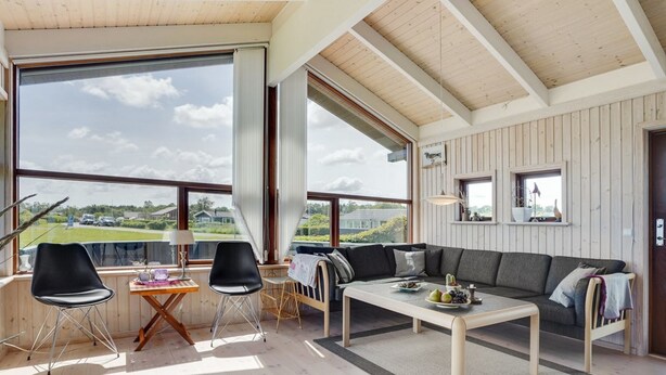 Een ruime woonkamer met een groot raam, een bank, een salontafel en twee stoelen.