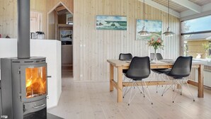 Een moderne keuken met een houtkachel, houten wanden en een eethoek met stoelen en een tafel.