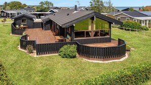 Een modern huis met een ruim terras, een overdekte zithoek en een groot raam.