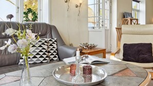 A modern living room with a grey sofa, a round coffee table, and a beige armchair. There is a vase with flowers on the coffee table, and a tray with two glass candle holders. - "Adine" - 13km from the sea by Interhome (Bredebro)