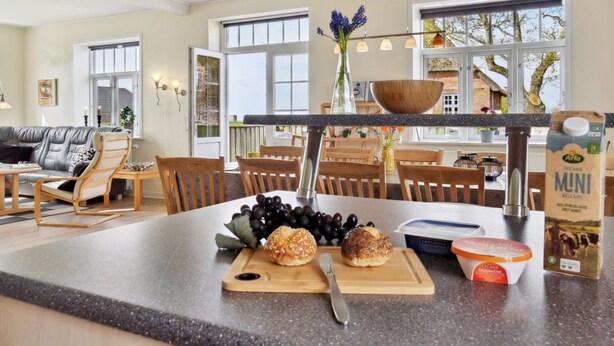 A modern kitchen with a granite countertop, a wooden island, and a dining area with wooden chairs and a table. - "Adine" - 13km from the sea by Interhome (Bredebro)