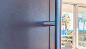 A modern interior with a dark-colored door, a metallic handle, and a view of a balcony with outdoor furniture. - Ripe Rosse ® -Residence- (Ogliastro Marina - Castellabate)