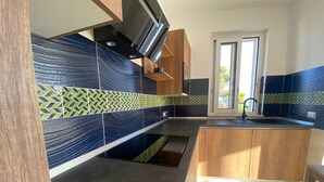 A modern kitchen with a black and green patterned backsplash, wooden cabinets, and a built-in oven. - Ripe Rosse ® -Residence- (Ogliastro Marina - Castellabate)