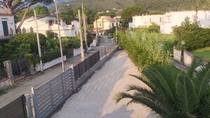 A residential street with houses, a gated entrance, and a palm tree. - Ripe Rosse ® -Residence- (Ogliastro Marina - Castellabate)
