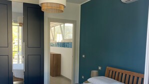 A bedroom with a large bed, a wooden headboard, a hanging light fixture, and a window with a view of greenery. - Ripe Rosse ® -Residence- (Ogliastro Marina - Castellabate)