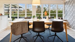 Een moderne eetruimte met een houten plafond, grote ramen en een tafel gedekt voor vier personen.