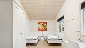 A modern bedroom with two single beds, a desk, a chair, a window, and a painting on the wall. - "Mahalia" - 300m from the sea by Interhome (Sydals)