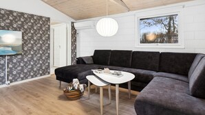 Een moderne woonkamer met een donkergrijze hoekbank, een witte salontafel en een hanglamp.