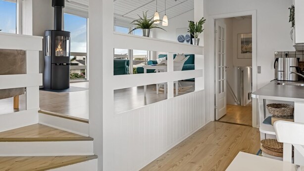 A modern kitchen with white cabinetry, a built-in stove, and a dining area with a wooden floor and white furniture. - "Stina" - 250m from the sea by Interhome (Løkken)