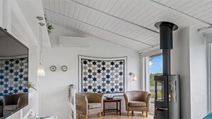 A modern living room with a fireplace, wooden flooring, and a large window offering a view. - "Stina" - 250m from the sea by Interhome (Løkken)