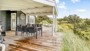 A covered outdoor area with a wooden deck, a dining table with chairs, and a view of the surrounding landscape. - "Stina" - 250m from the sea by Interhome (Løkken)
