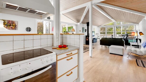Une cuisine moderne dotée d’une cuisinière intégrée, de meubles en bois et d’une grande fenêtre.