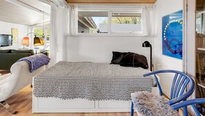 Une chambre à coucher avec un lit, une chaise, une fenêtre et un tableau accroché au mur.
