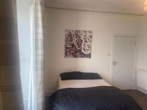 A bedroom with a bed, a door, and a painting on the wall. - Studio Apartments (Langbank)