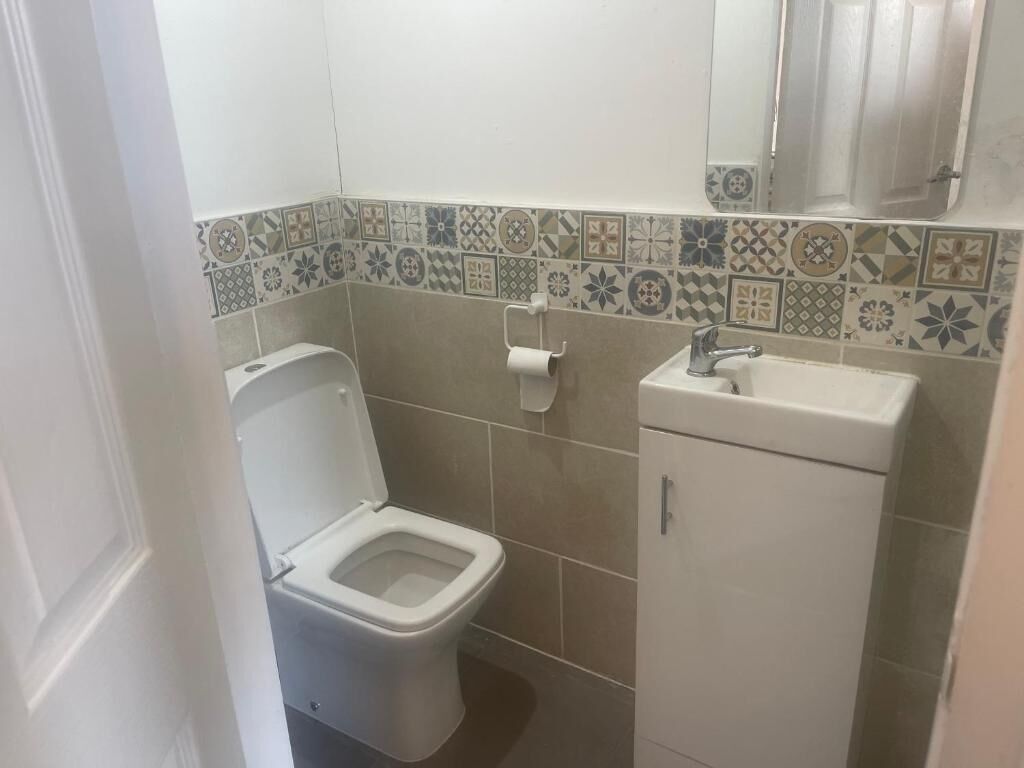 Et lille badeværelse med toilet, håndvask og spejl.