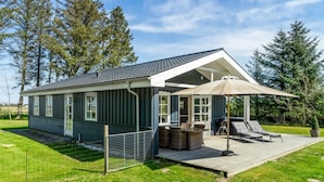 A modern house with a covered patio, a fenced yard, and a view of the surrounding forest. - "Nanja" - 759m from the sea by Interhome (Løkken)