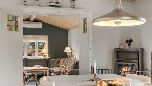 Ein Essbereich mit Tisch für zwei Personen, einem Kamin und Blick ins Freie.